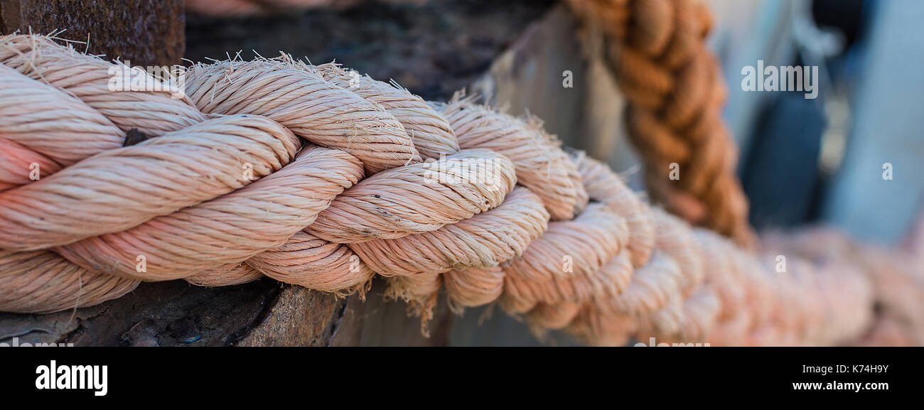 Ropes on Old Rusty Ship Closeup. Old Frayed Boat Rope as a Nautical Background. Naval Ropes on a Pier. Vintage Nautical Knots. Big Marine Sea Ship Rop Stock Photo
