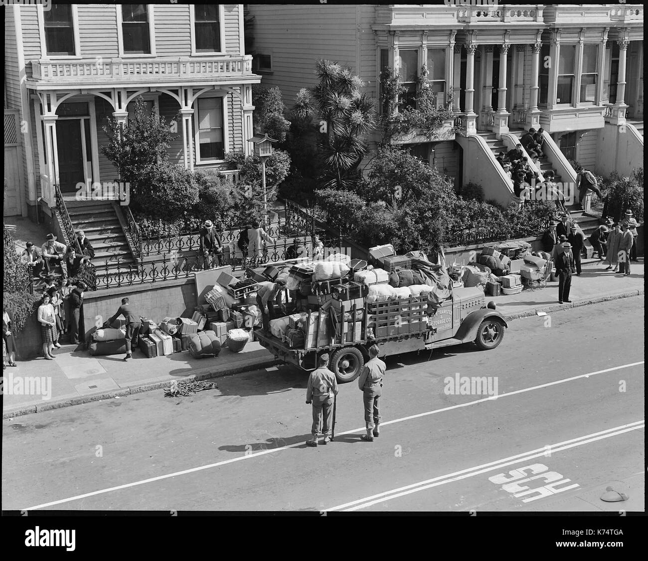 Soldiers guard bed-rolls and luggage of residents being evacuated from the Japanese quarter as evacuees wait for transportation, San Francisco, CA, 4/29/1942. Photo by Dorothea Lange Stock Photo