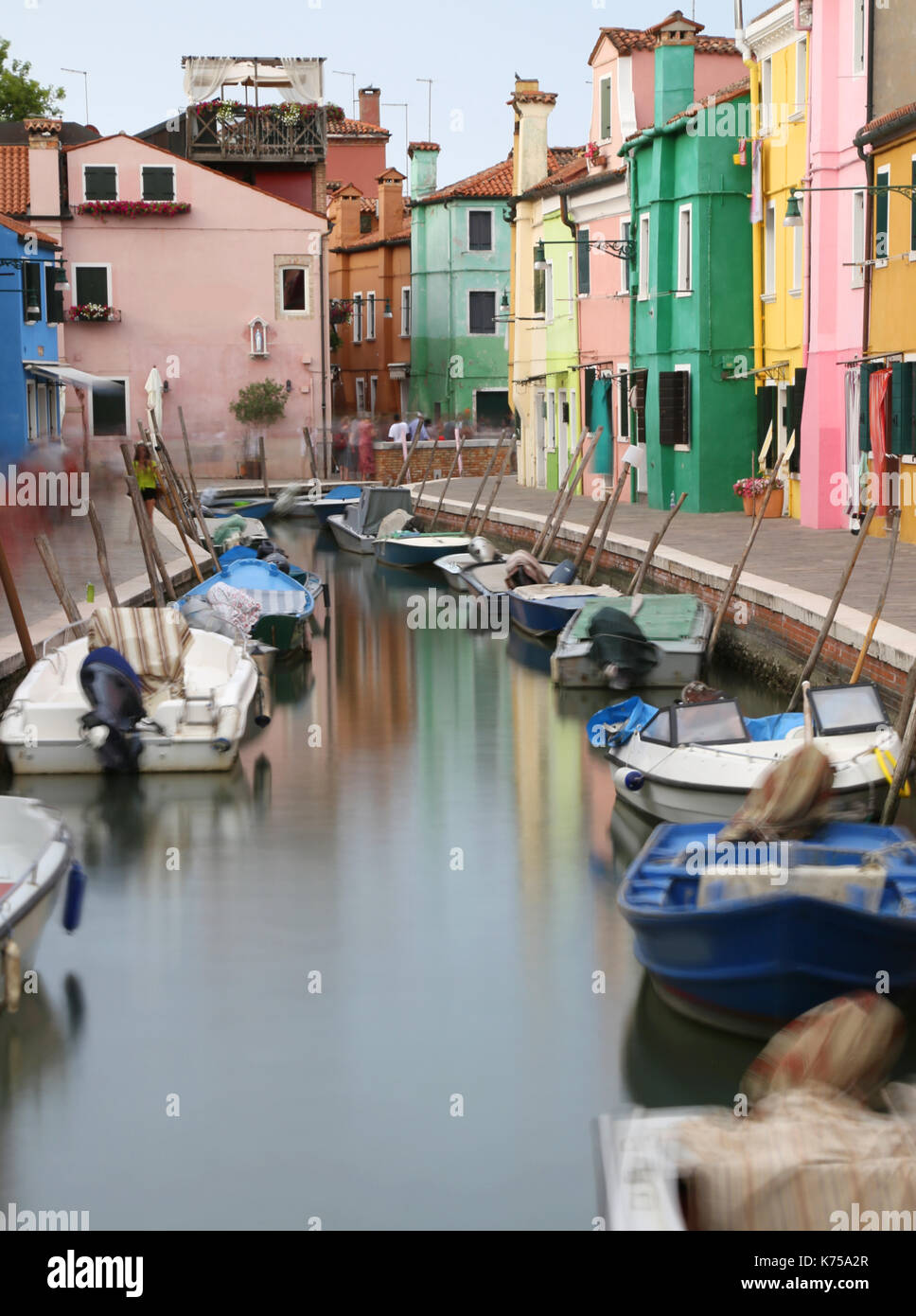 navigable canal and the colorful houses of the BURANO island near Venice with moving boats due to the long exposure time . The houses are not moved. Stock Photo
