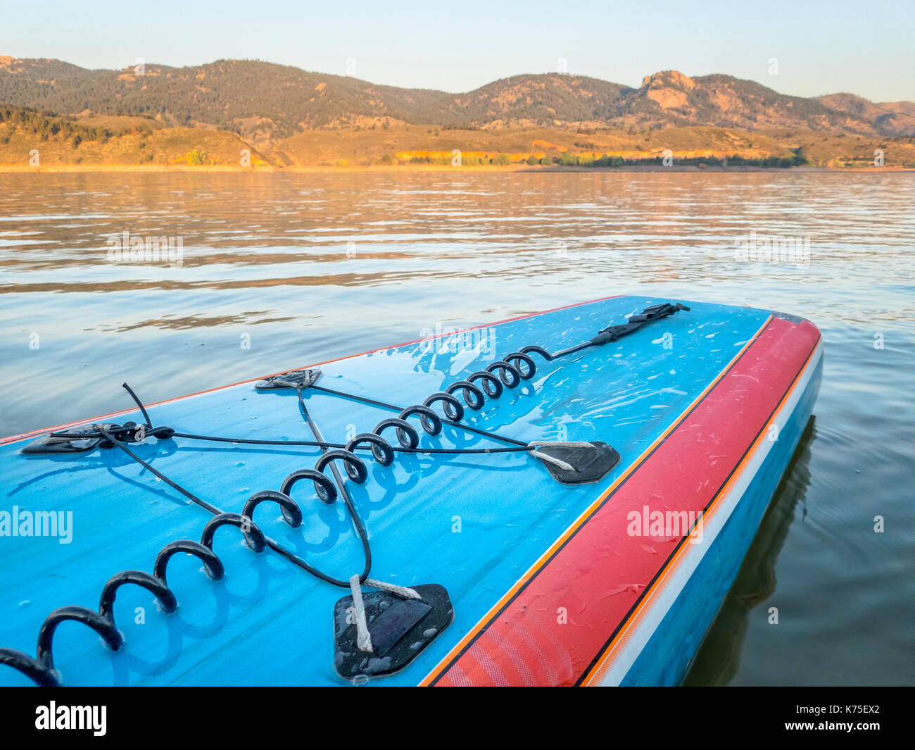 A tail of stand up paddleboard with a leash and bungees on a mountain