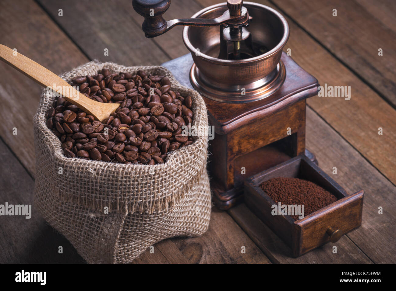 Grinding coffee from roasted beans into a rustic bag. Stock Photo