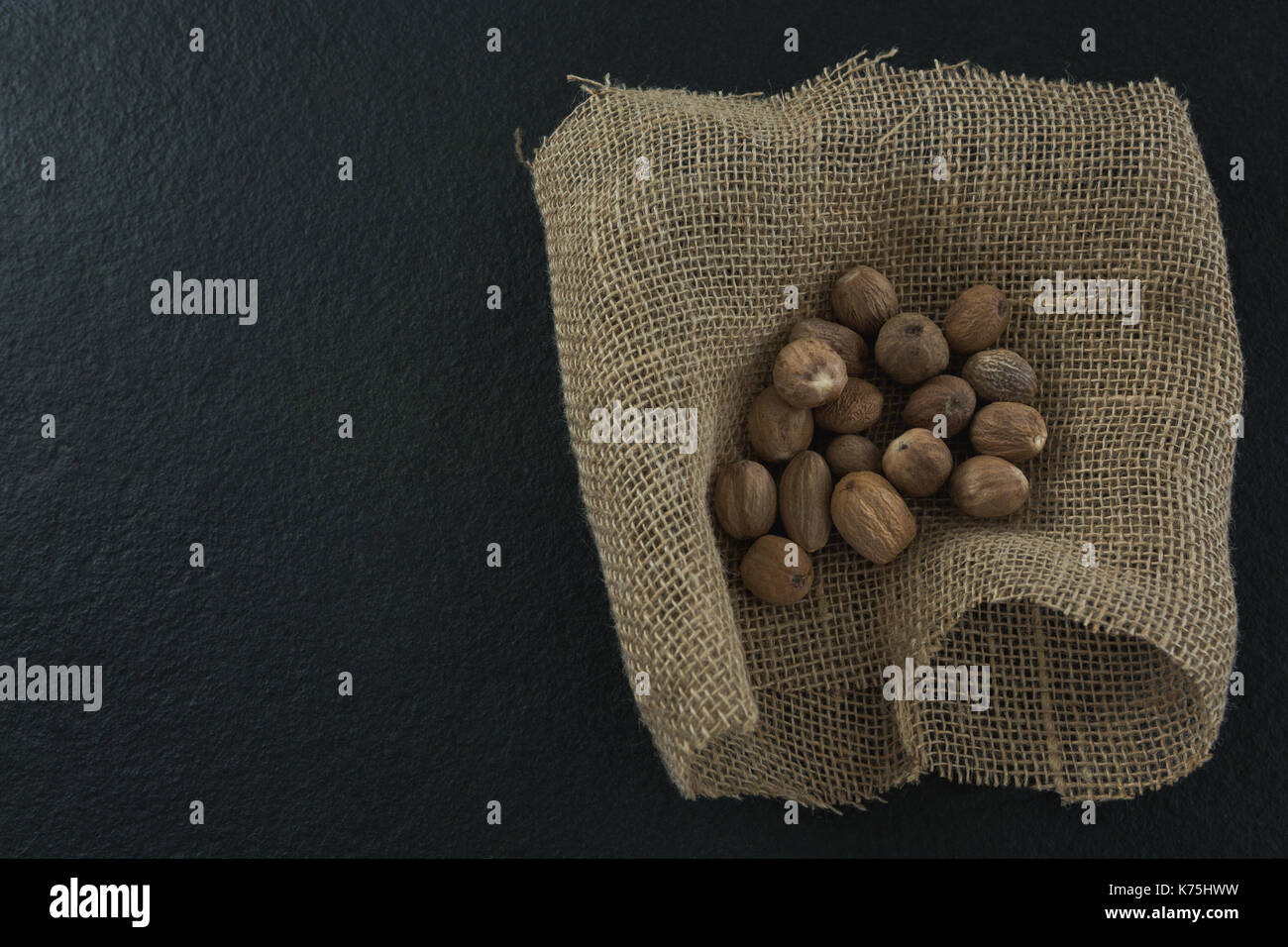 Close-up of nutmegs in sack on black background Stock Photo