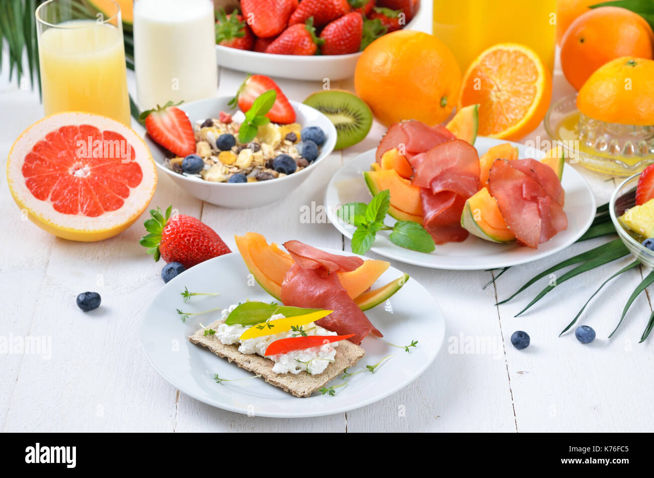 Healthy breakfast with fresh fruit, crispbread with cottage cheese and lean ham on melon Stock Photo