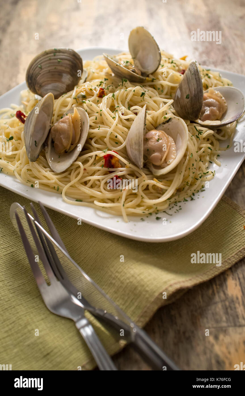 Spaghetti with fresh cooked baby clam sauce on rustic wood table Stock