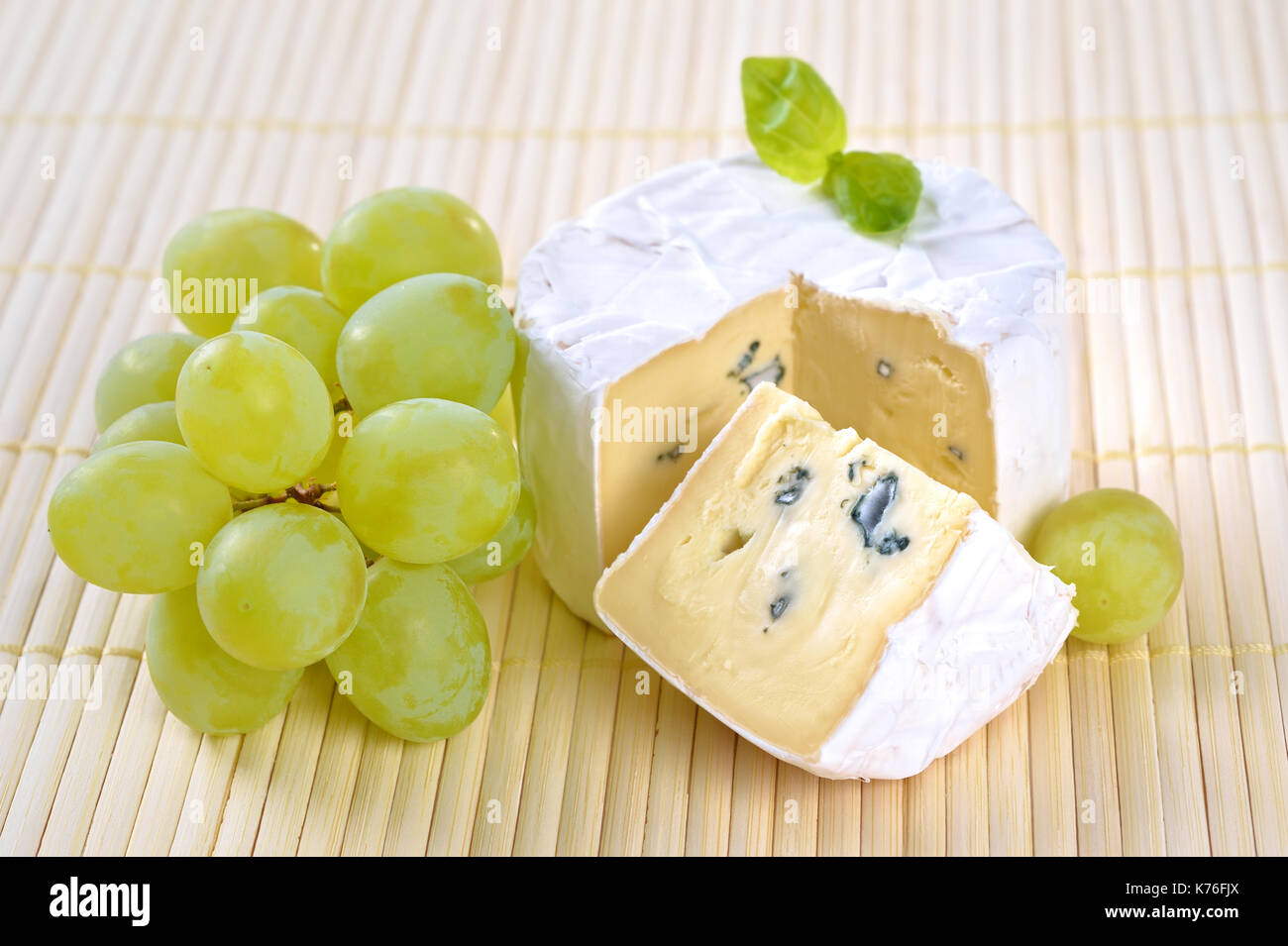 French Camembert soft cheese with grapes and marjorjam on an wooden placemat Stock Photo