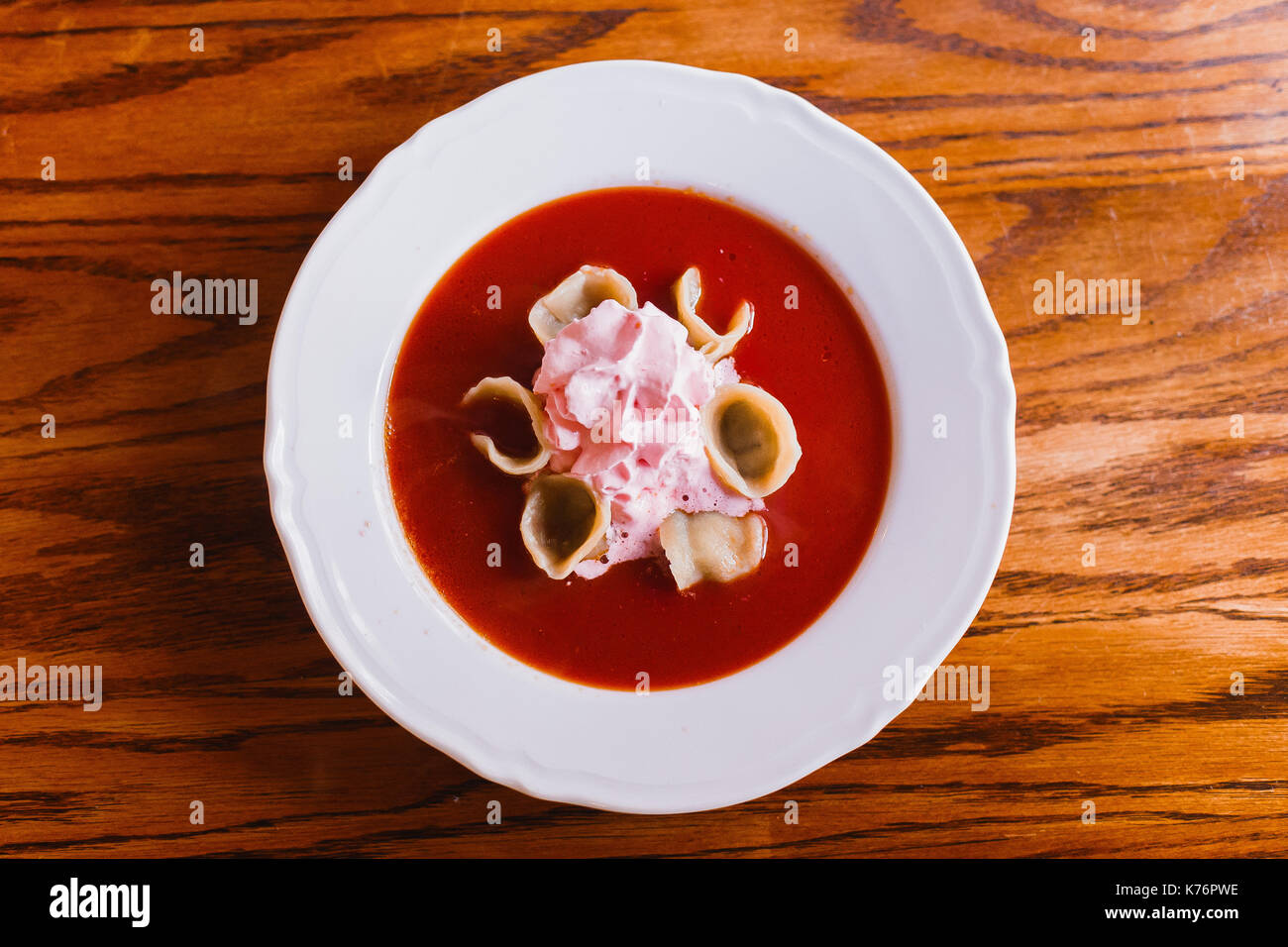 The above view of the borsch with dumplings and sour cream placed on the wooden table. Stock Photo