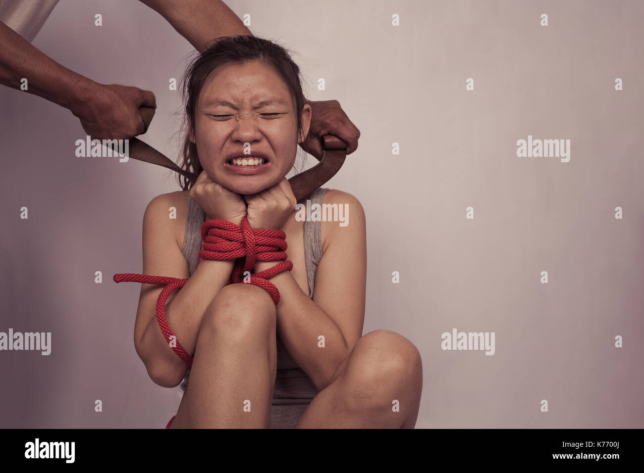 a woman with hands tied up with rope being abused, struggle, terrified, and threaten from domestic violence and abuse,trafficking Concept Stock Photo