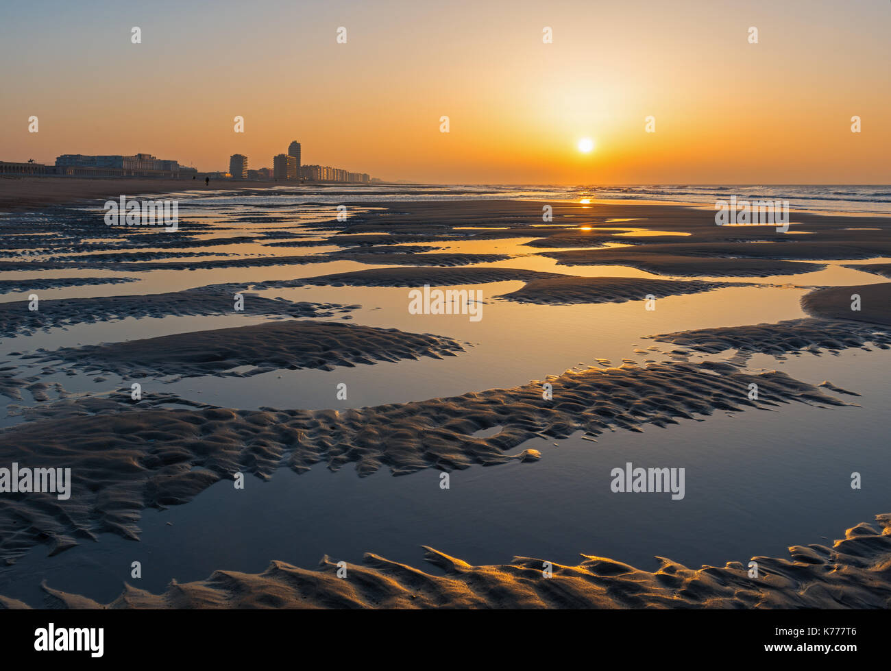 Sunset on the North Sea beach of Oostende with a view over its skyline and sand patterns. Stock Photo