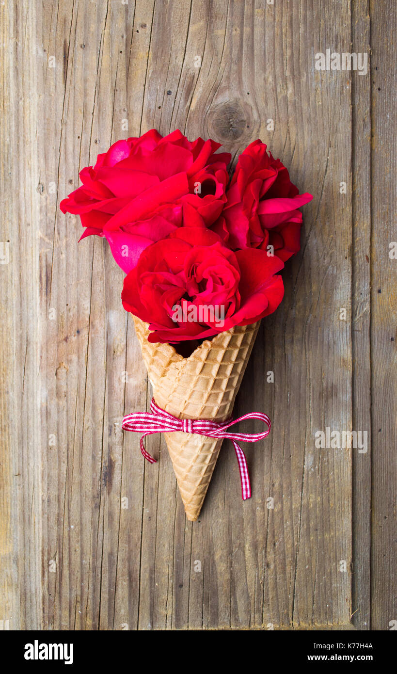 Red roses bouquet in an ice cream cone on rustic background Stock Photo