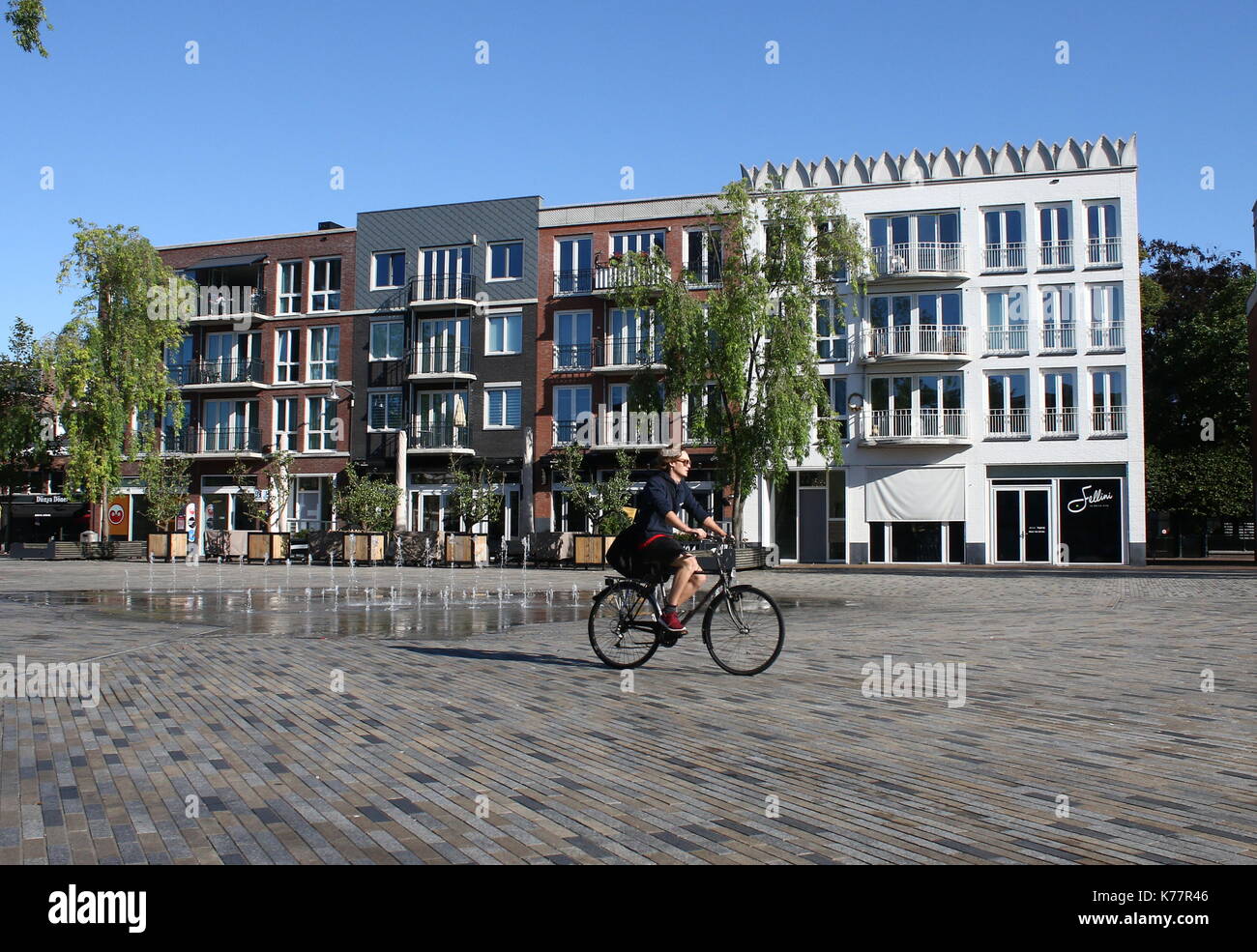 Young woman cycling in summer on the renovated central Zaailand square in Leeuwarden, Friesland, Netherlands Stock Photo