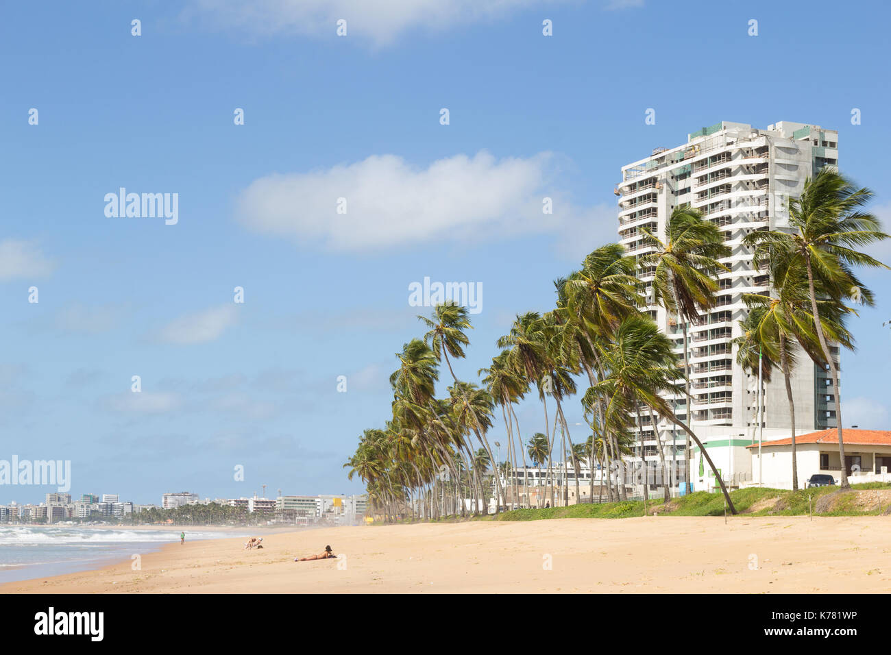 Maceio, Brazil - September, 05 2017. Cruz das Almas beach with large coconut trees and a building in the background. The coastal strip is almost deser Stock Photo