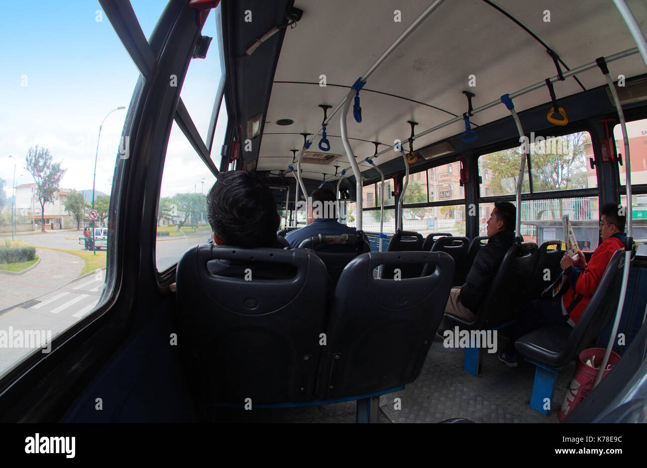 People sitting inside a public transport bus in the city of Cuenca. Wide angle Stock Photo