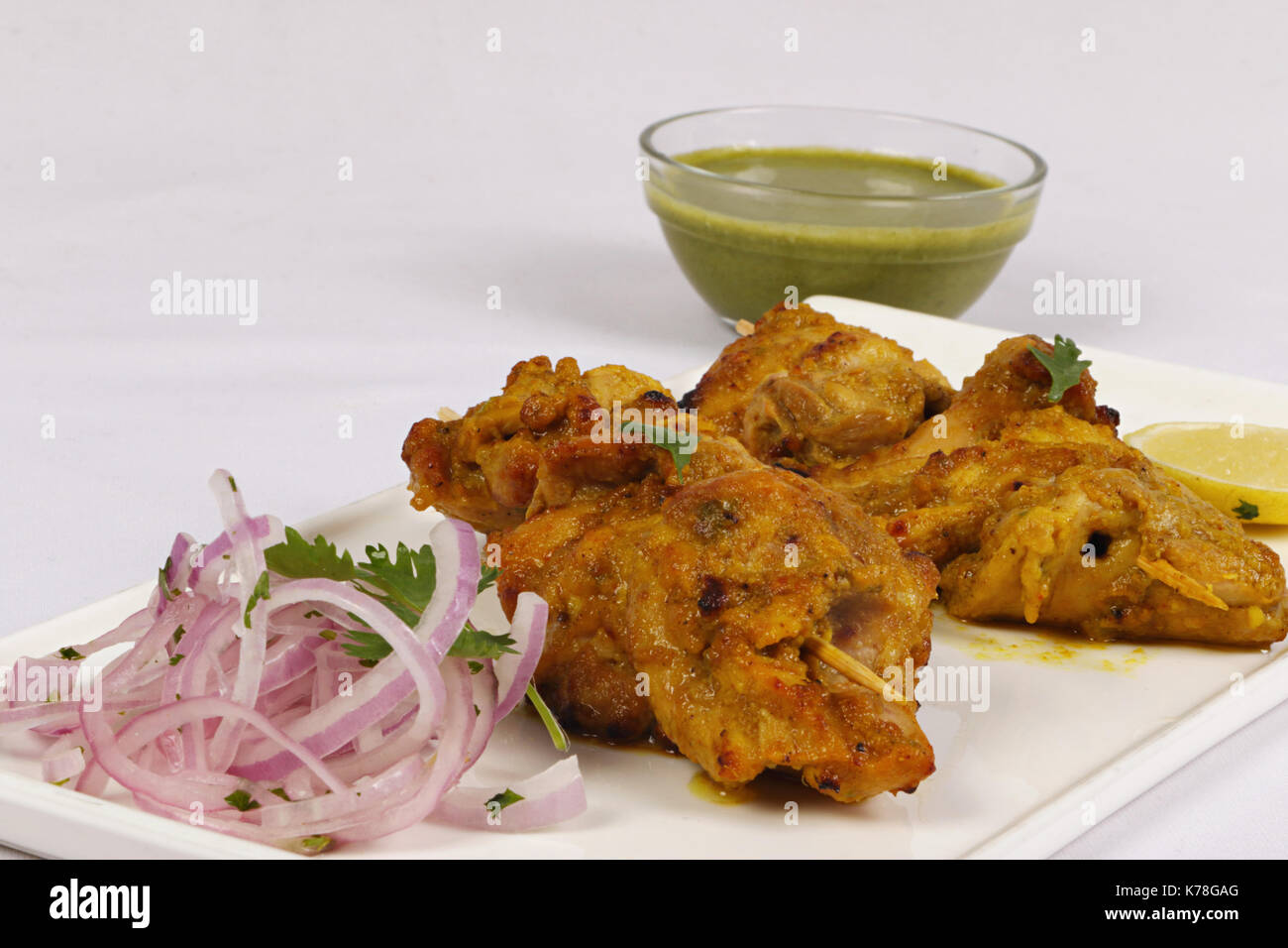 Chicken Tikka Kebab with mint sauce, lime and sliced onions Stock Photo