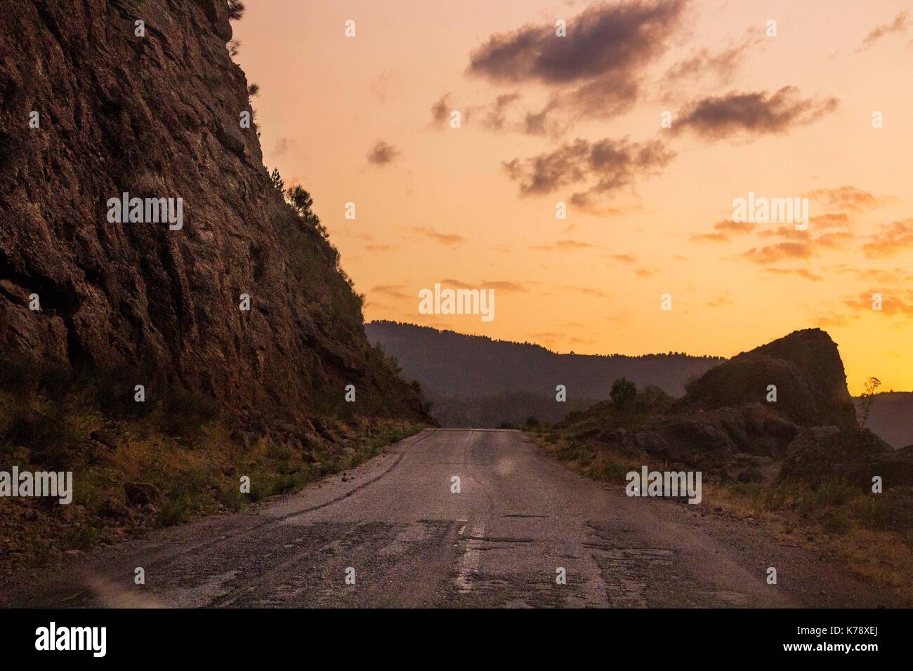 driving to the sunset taking the high road with the rocks on one side and the cliff edge to the other Stock Photo