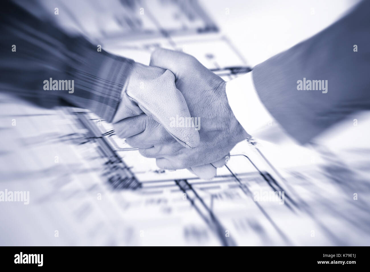 Worker and a businessman shaking hands over house renovation plans house renovation contract deal and plans Stock Photo