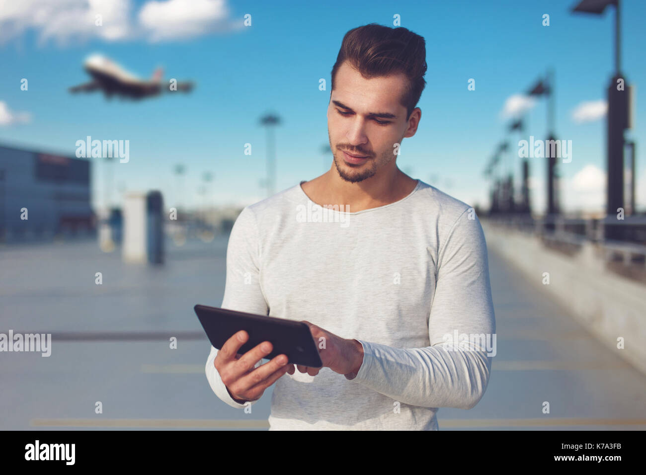 Young man buying air ticket at airport by tablet, wireless technology Stock Photo