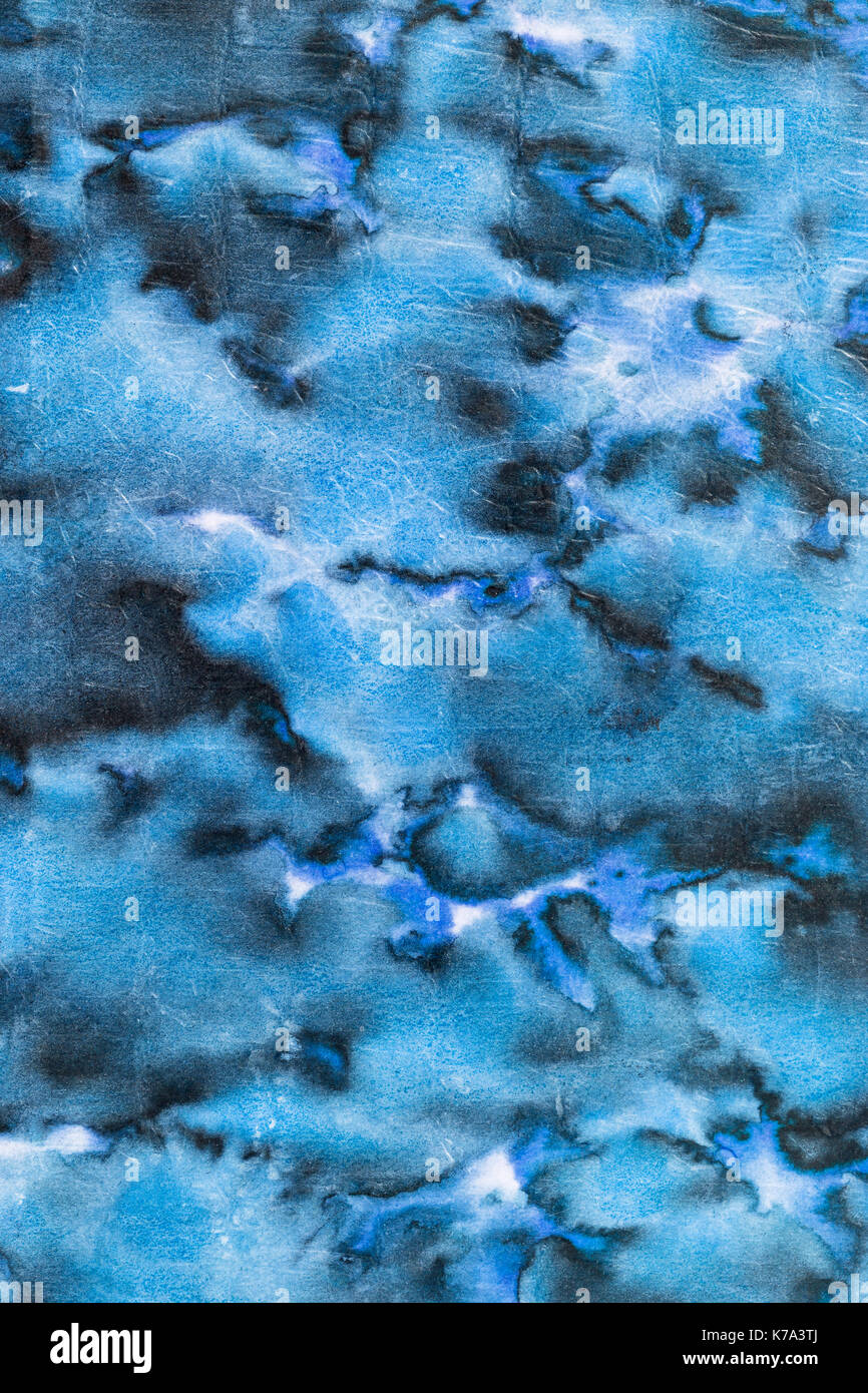 Light and dark stained blue abstract cloudy pattern from an aged retro paperback as a grunge background image Stock Photo