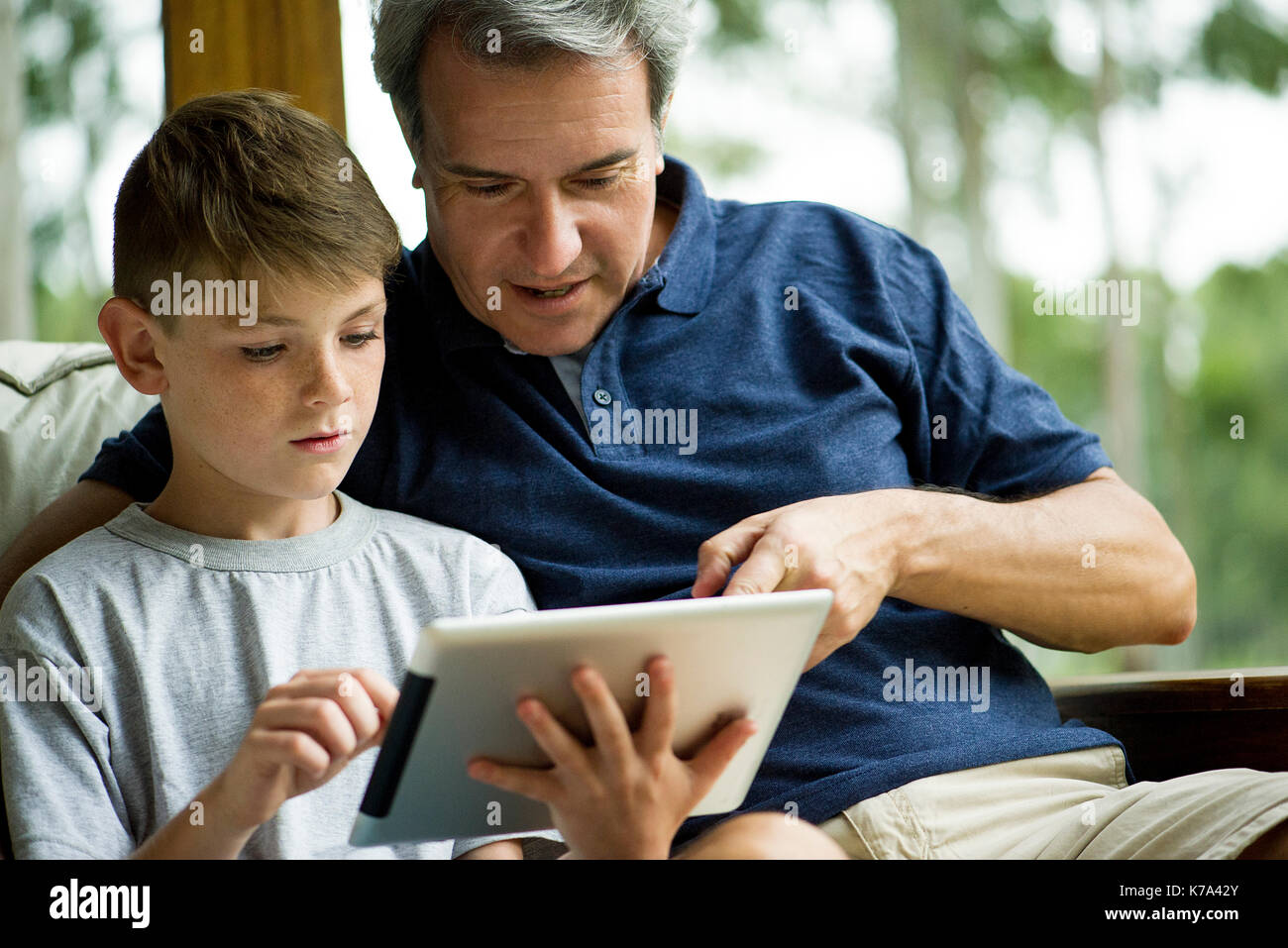 Man with child using digital tablet Stock Photo