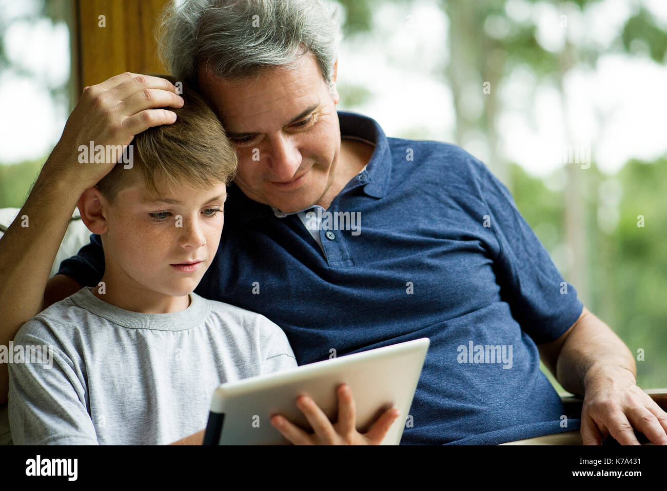 Man with child using digital tablet Stock Photo