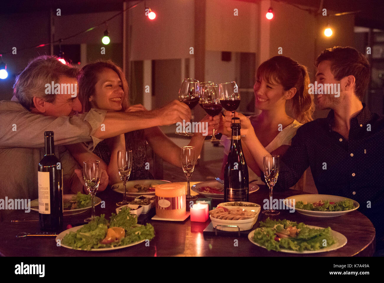 Friends clinking wine glasses at dinner party Stock Photo