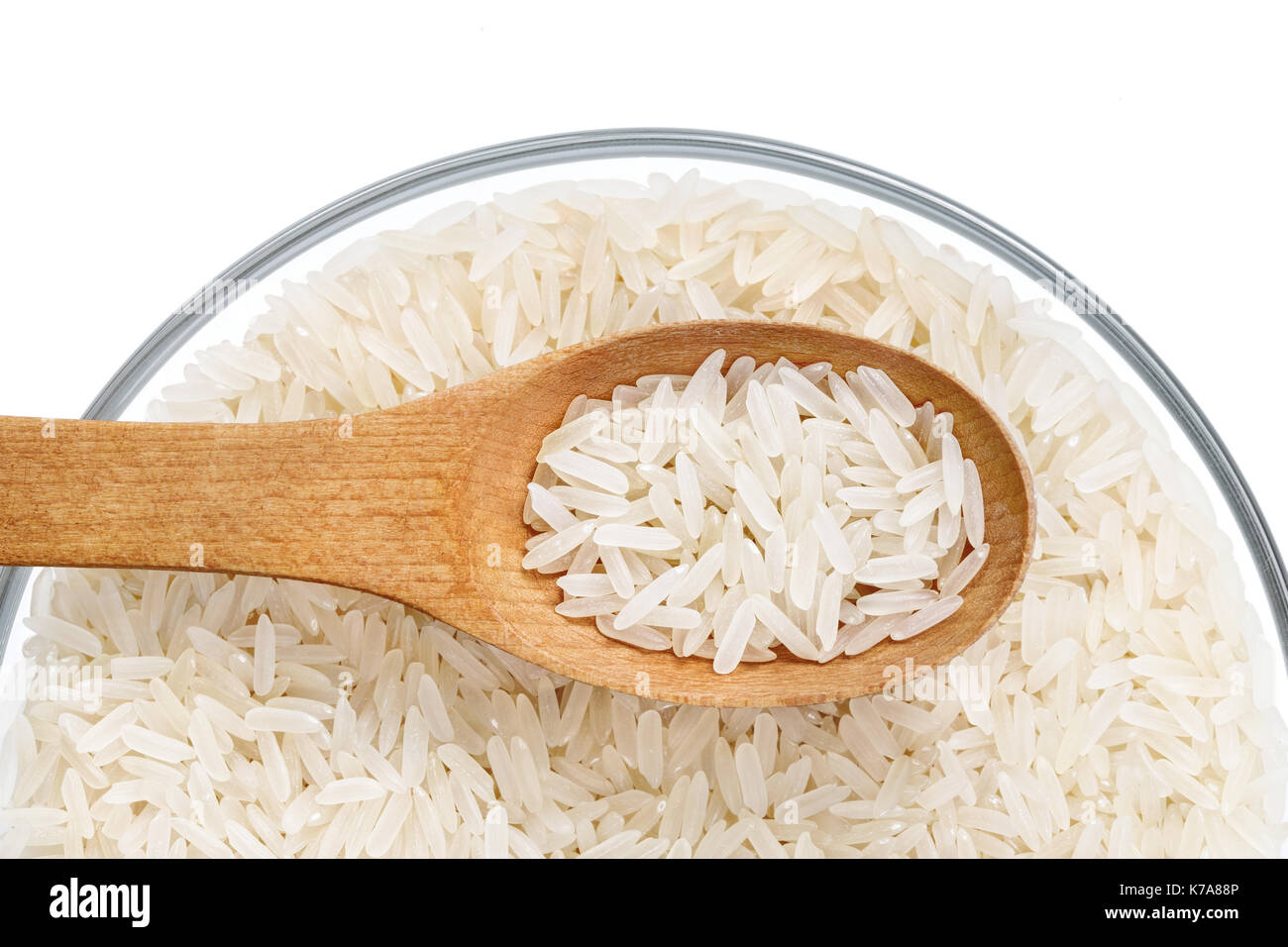 Healthy food. Parboiled rice and wooden spoon in glass bowl on white background. Close up. Top view. High resolution product. Stock Photo