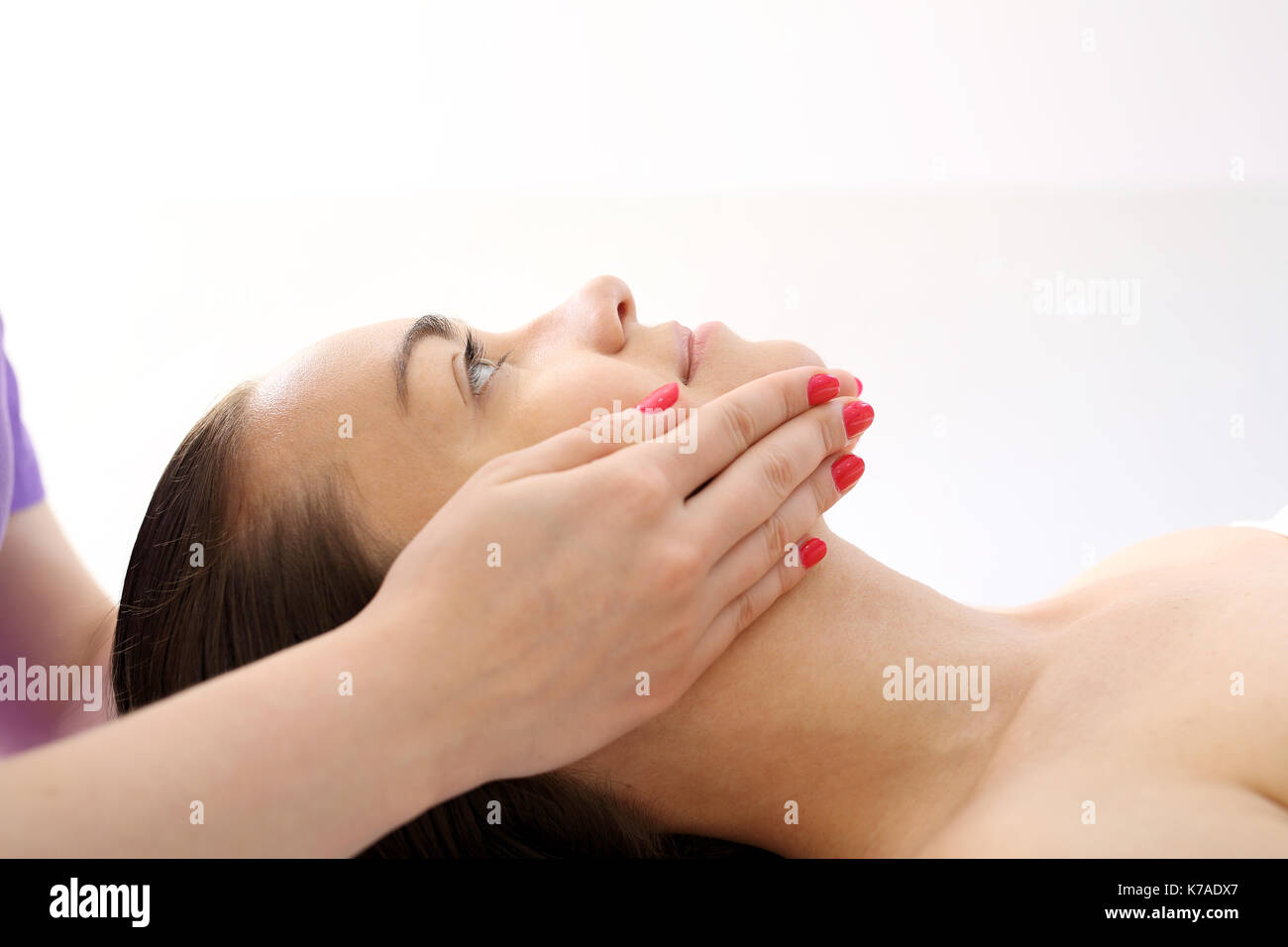 Relaxing facial massage. Woman in beauty parlor during facial massage. Stock Photo