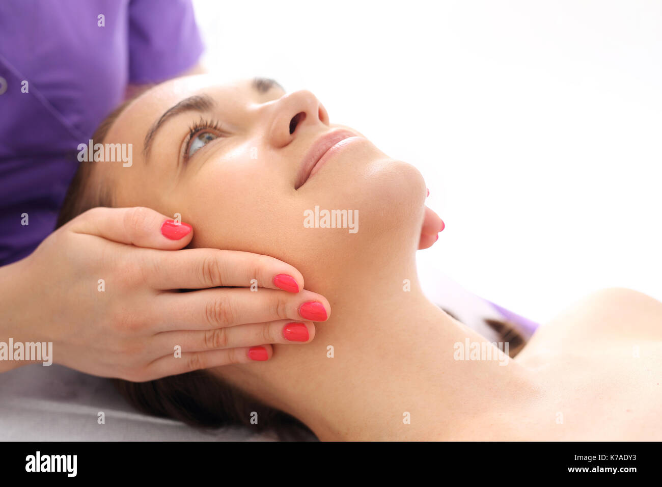 Professional face massage. Woman in beauty parlor during facial massage. Stock Photo