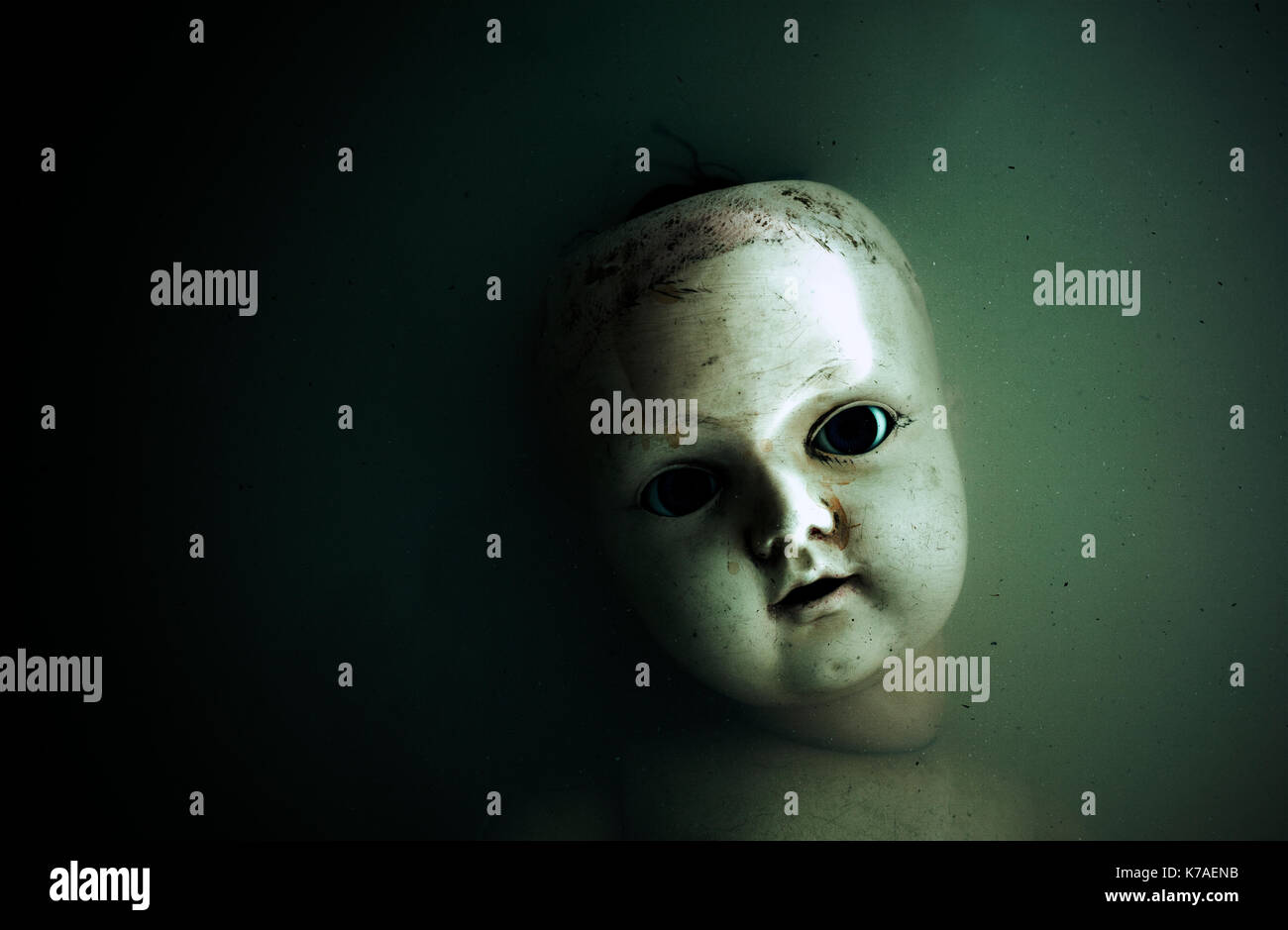 Creepy doll face in dark dirty water Stock Photo