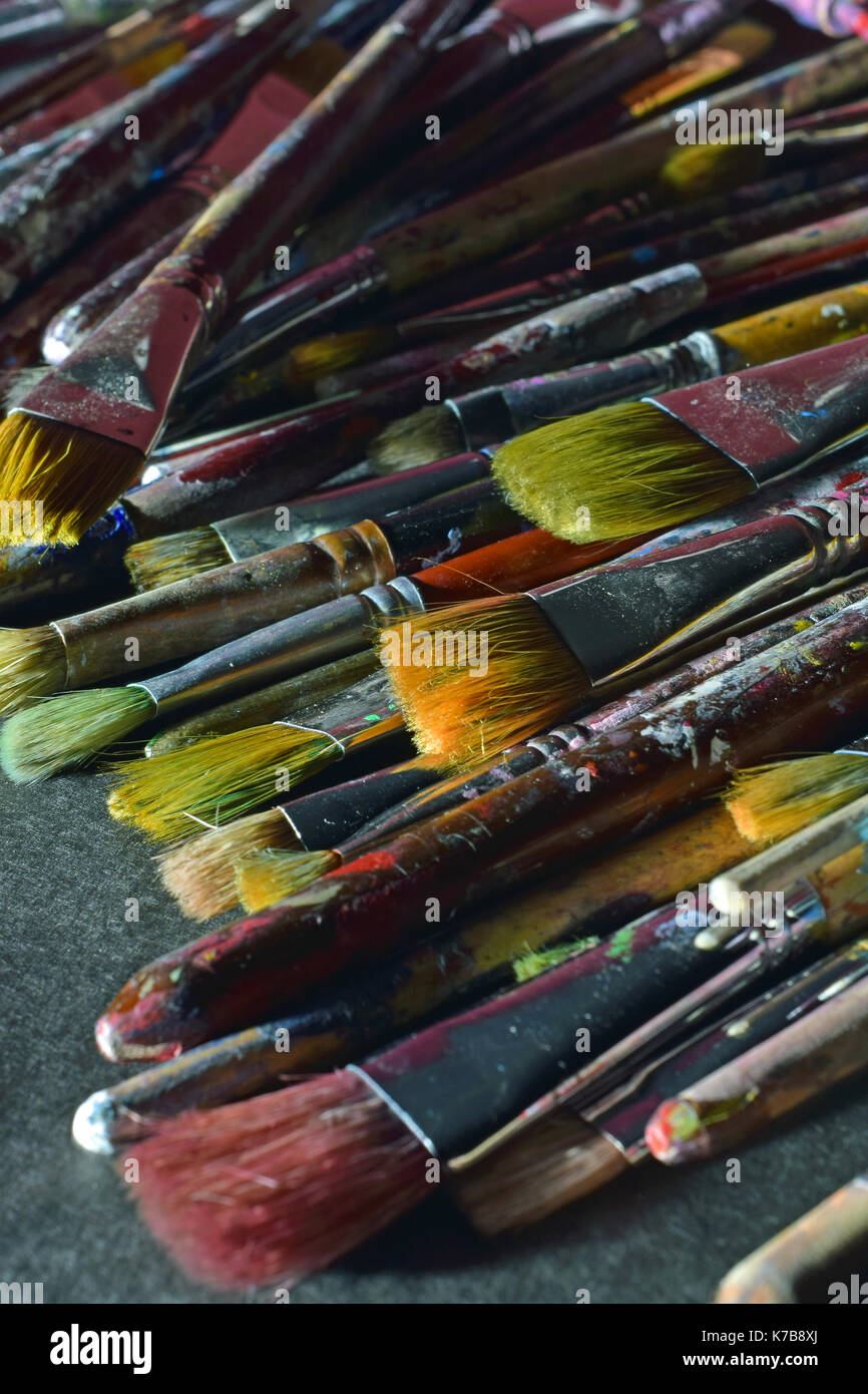 Stack of used paintbrushes on black surface. Vertical close up image. Stock Photo