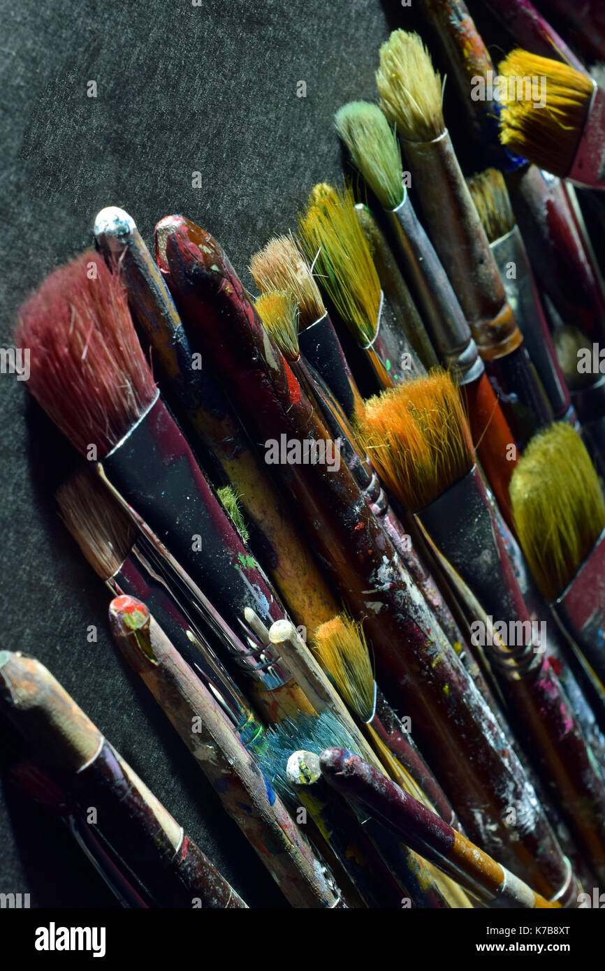 Stack of used paintbrushes on black surface. Vertical close up image. Stock Photo