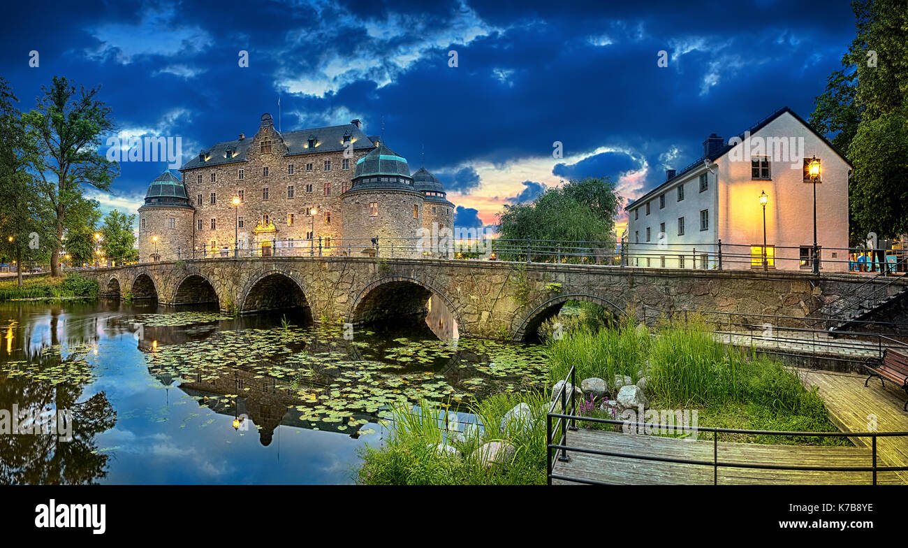Panoramic HDR image of Orebro Castle and bridge reflecting in water of Svartan river at dusk, Sweden Stock Photo