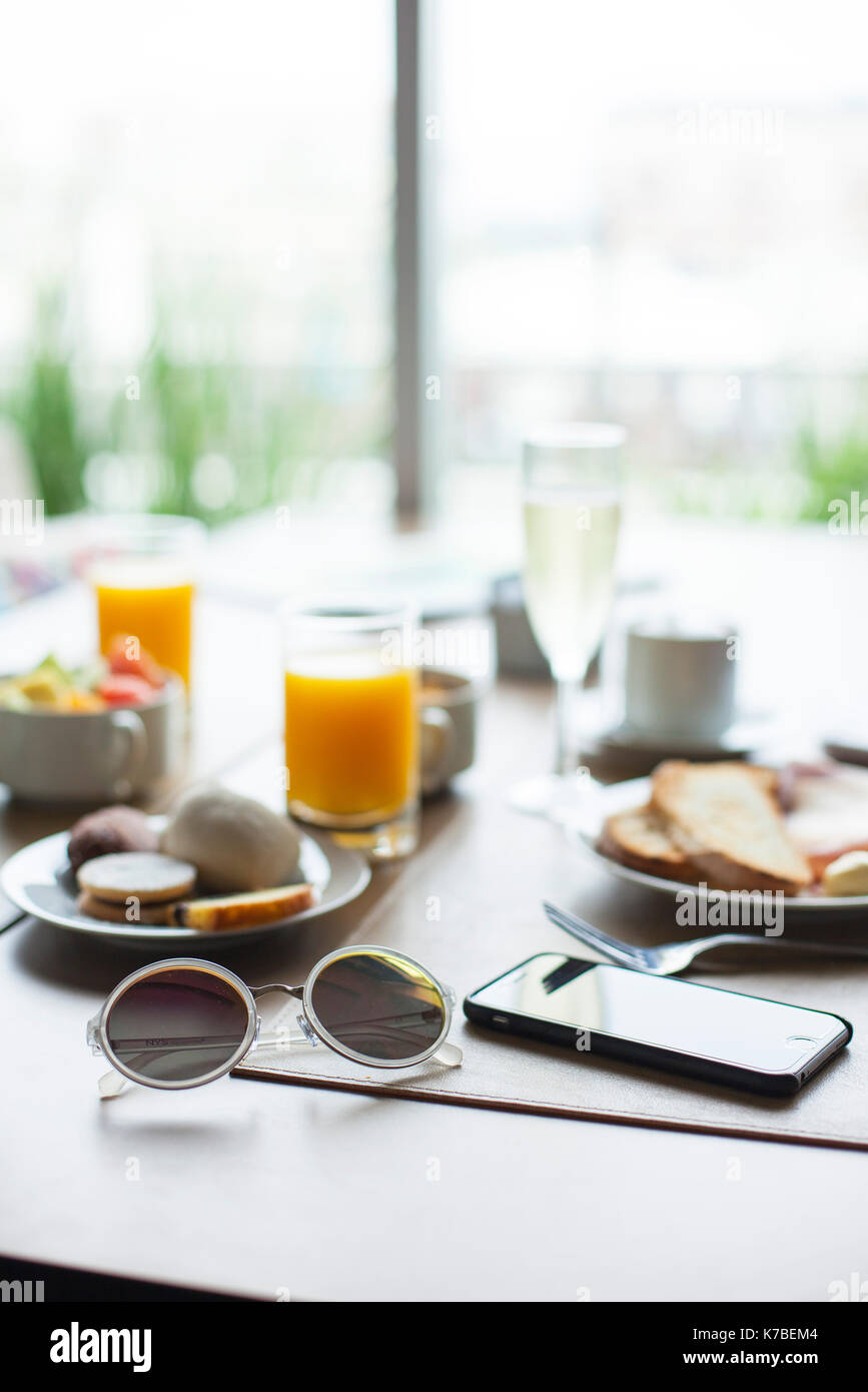 Sunglasses and smartphone on breakfast table in cafe Stock Photo