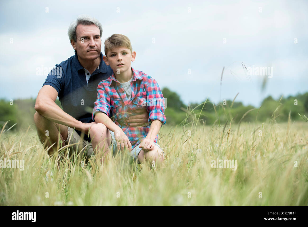Father and son crouching together in tall grass Stock Photo - Alamy