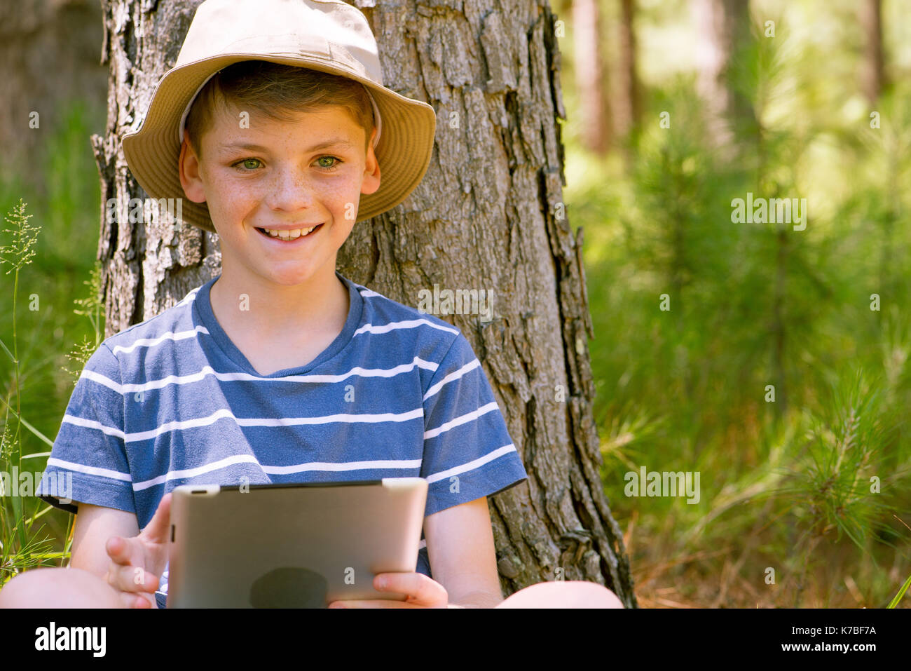 Boy using digital tablet in woods Stock Photo