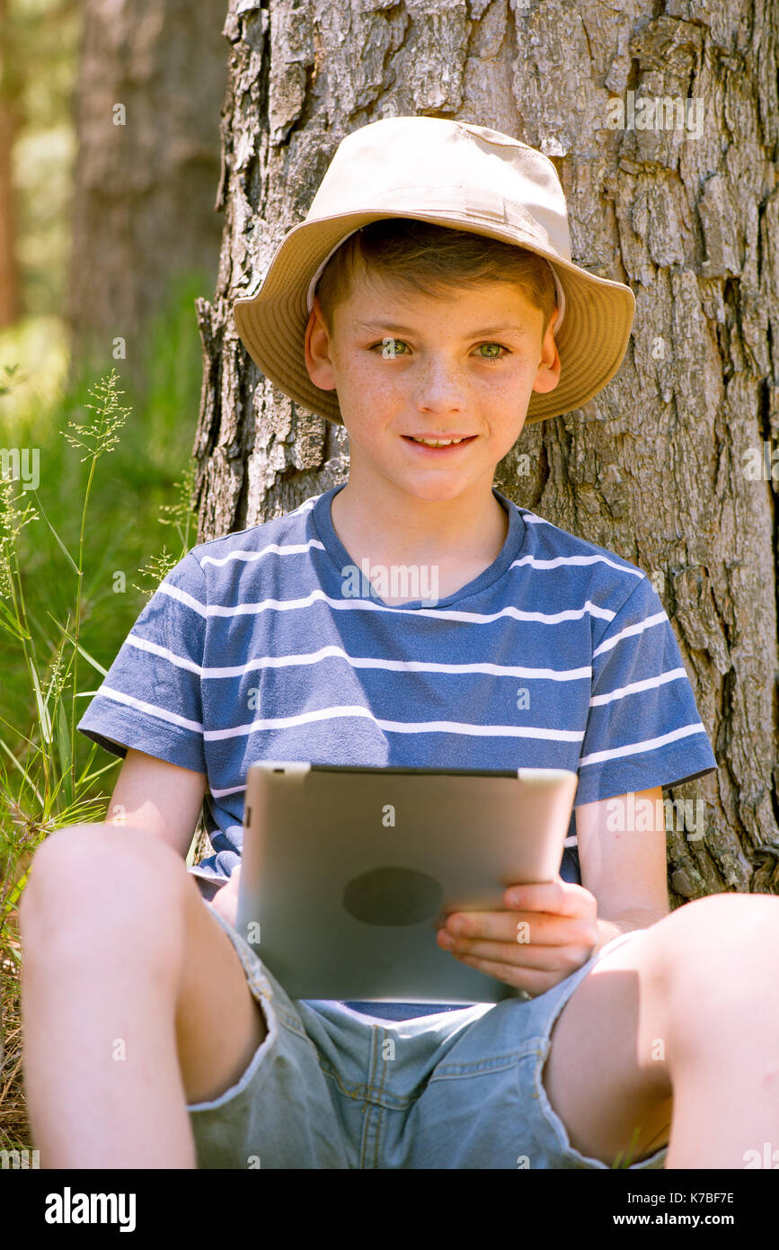 Boy using digital tablet in woods Stock Photo