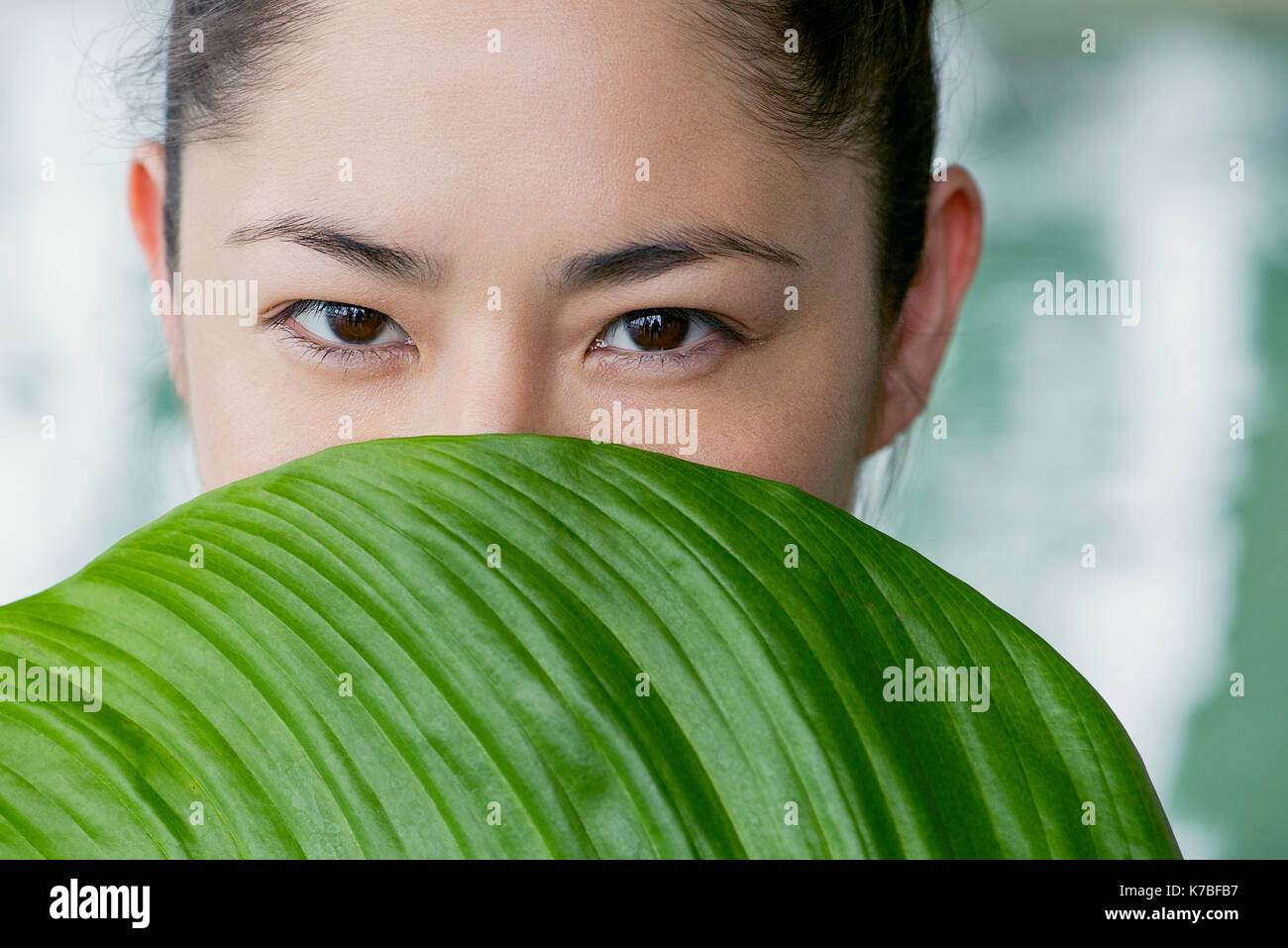 Young woman holding large leaf in front of her face Stock Photo