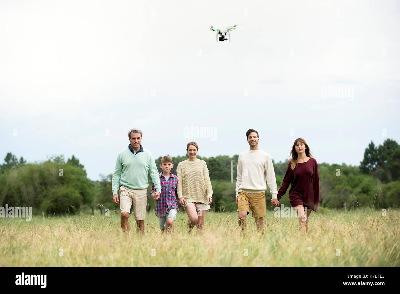 Family walking togther in field while drone flies overhead Stock Photo
