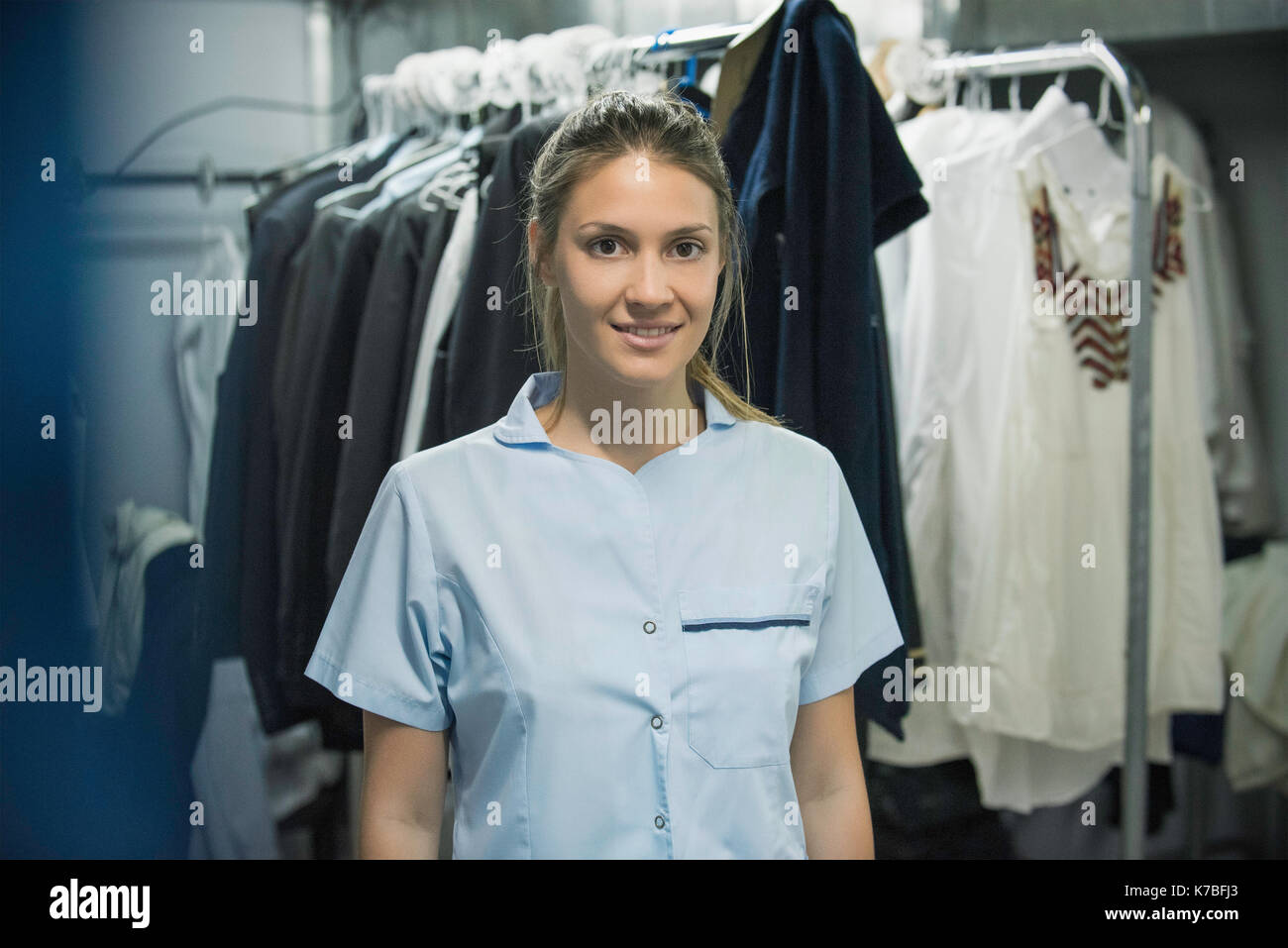 Young woman with clothes racks in foreground, portrait Stock Photo