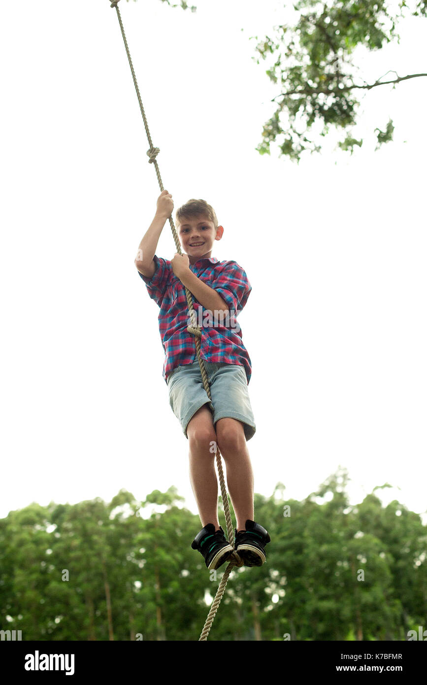 Boy swinging on rope outdoors Stock Photo