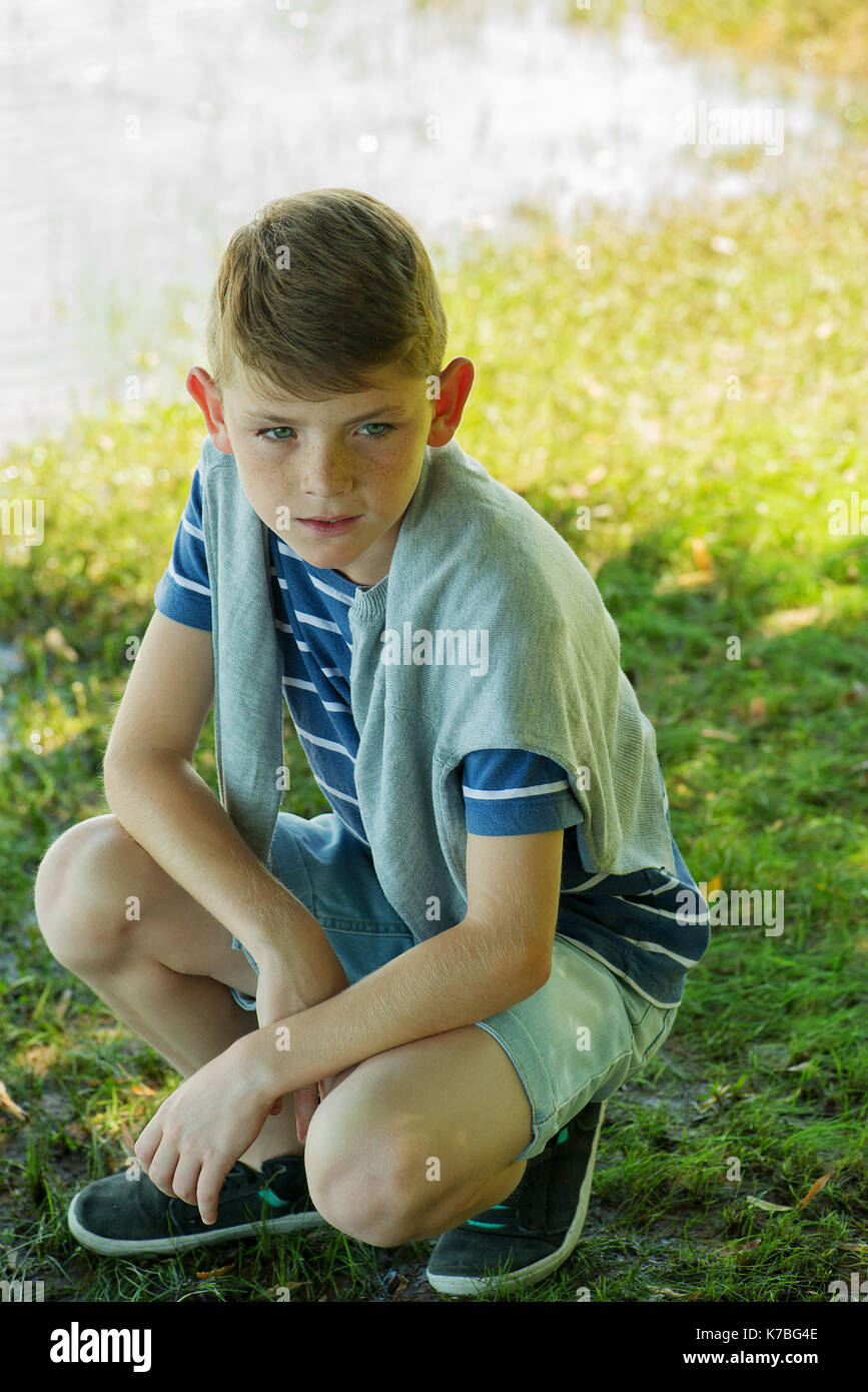 Boy crouching in nature Stock Photo