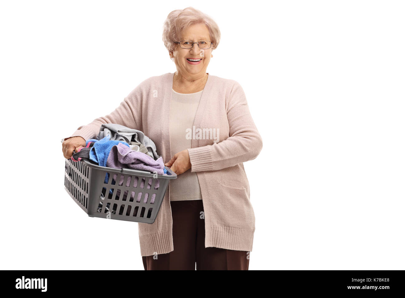 Elderly woman holding a laundry basket filled with clothes isolated on white background Stock Photo