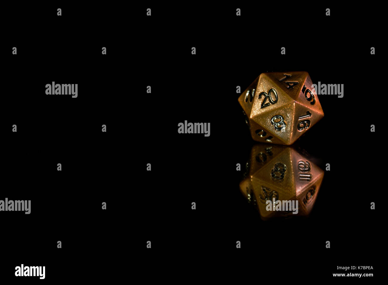 A twenty sided  polyhedral die on a mirrored surface. These type of dice are used for role playing games such as Dungeons & Dragons. Stock Photo