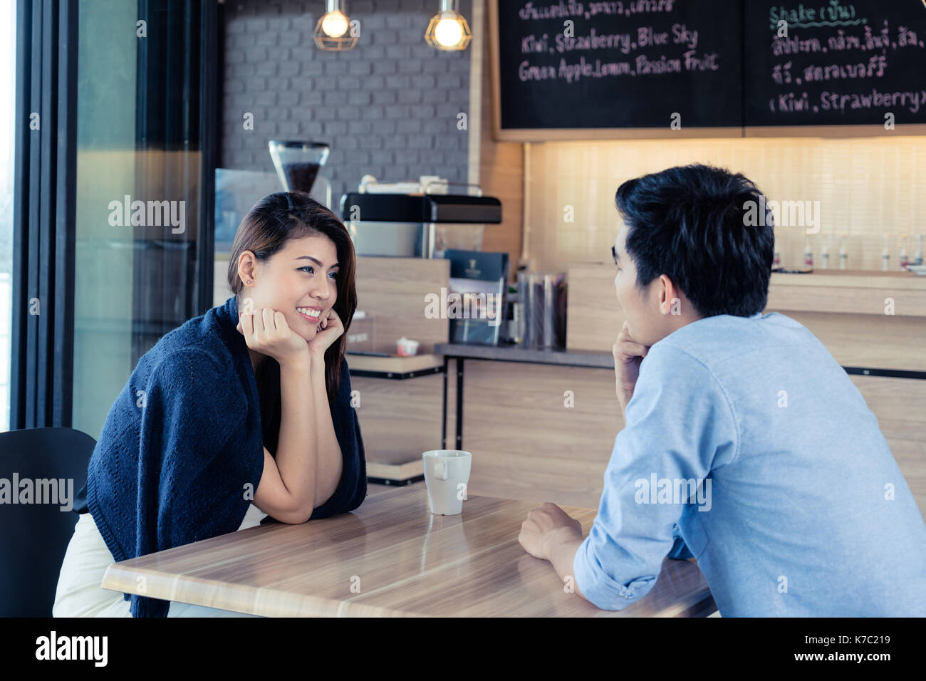 Dating in a cafe. Beautiful Asian lover couple sitting in a cafe enjoying in coffee and conversation. Love and romance. Stock Photo