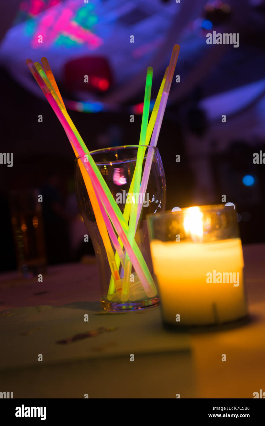 Colorful glow sticks on table at disco club party with candle Stock Photo