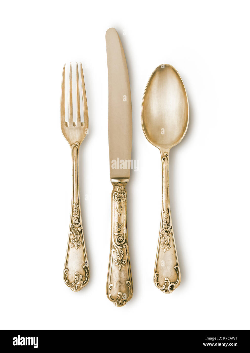 Golden cutlery set against white background with a soft shadow. Really ancient pieces with marks and texture. Clipping path Stock Photo