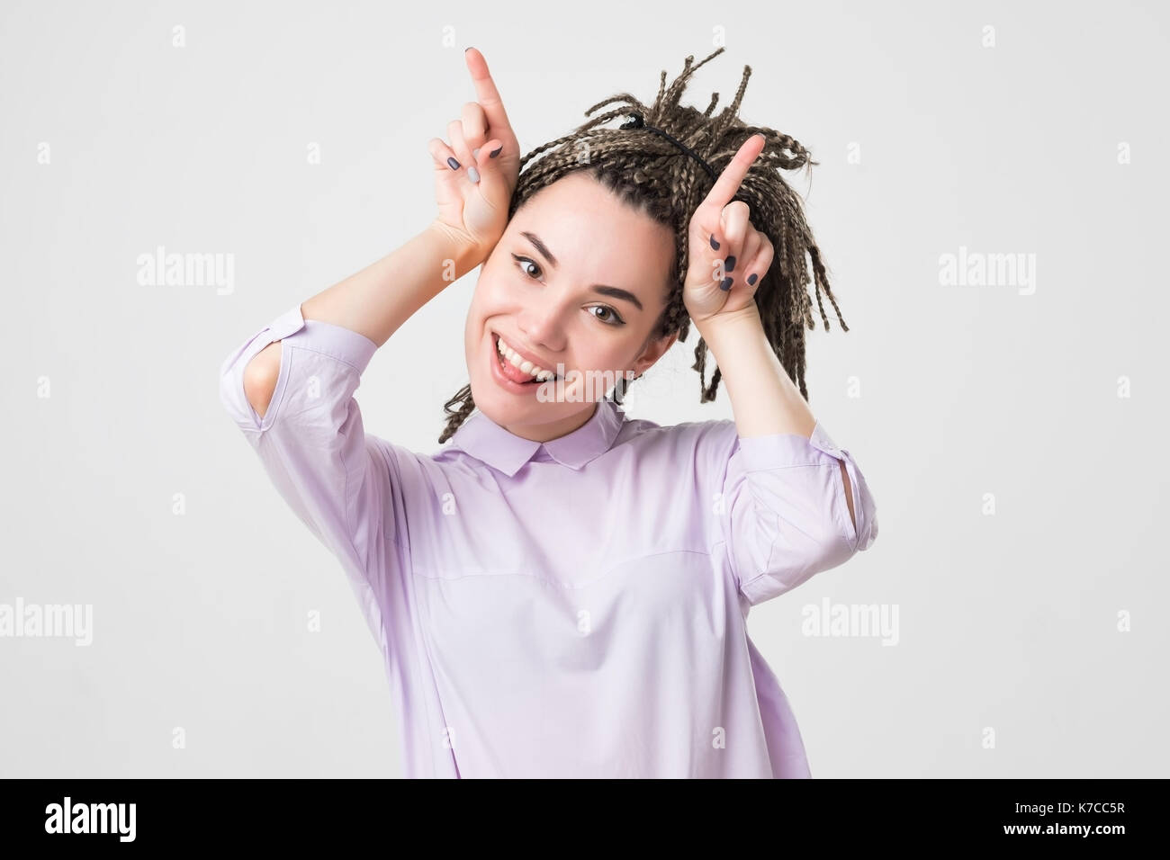 Playful teen girl with braids shows horns Stock Photo