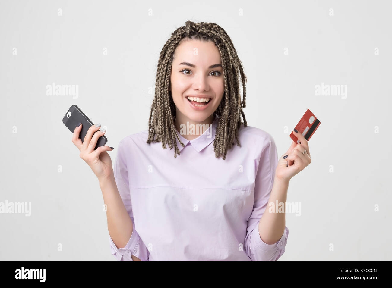 Happy caucasian european young woman holding phone and card making order online. Internet bank and online shopping technology concept Stock Photo