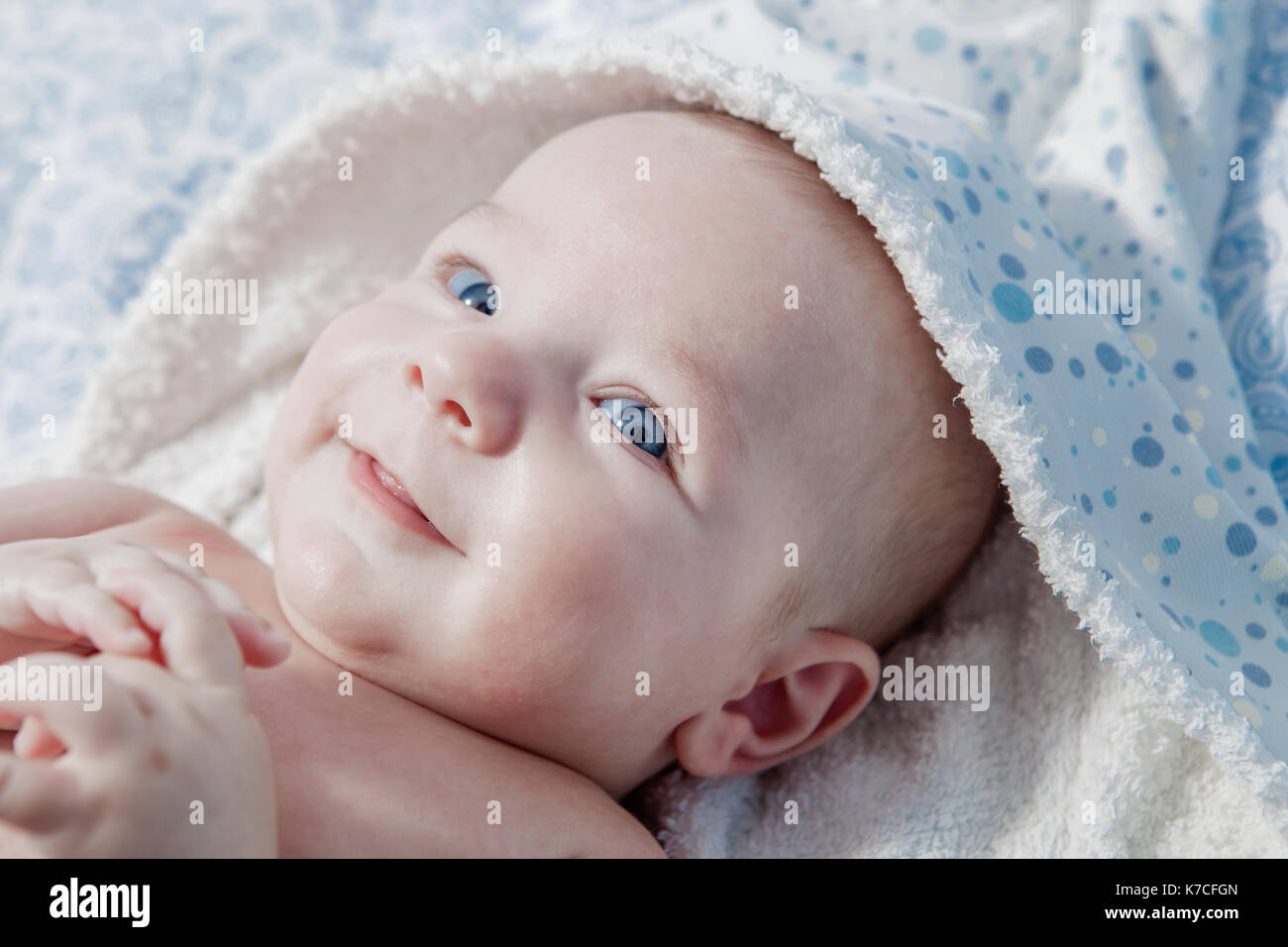 Cute three month baby wrapped bath towel after bath in bed at home Stock Photo