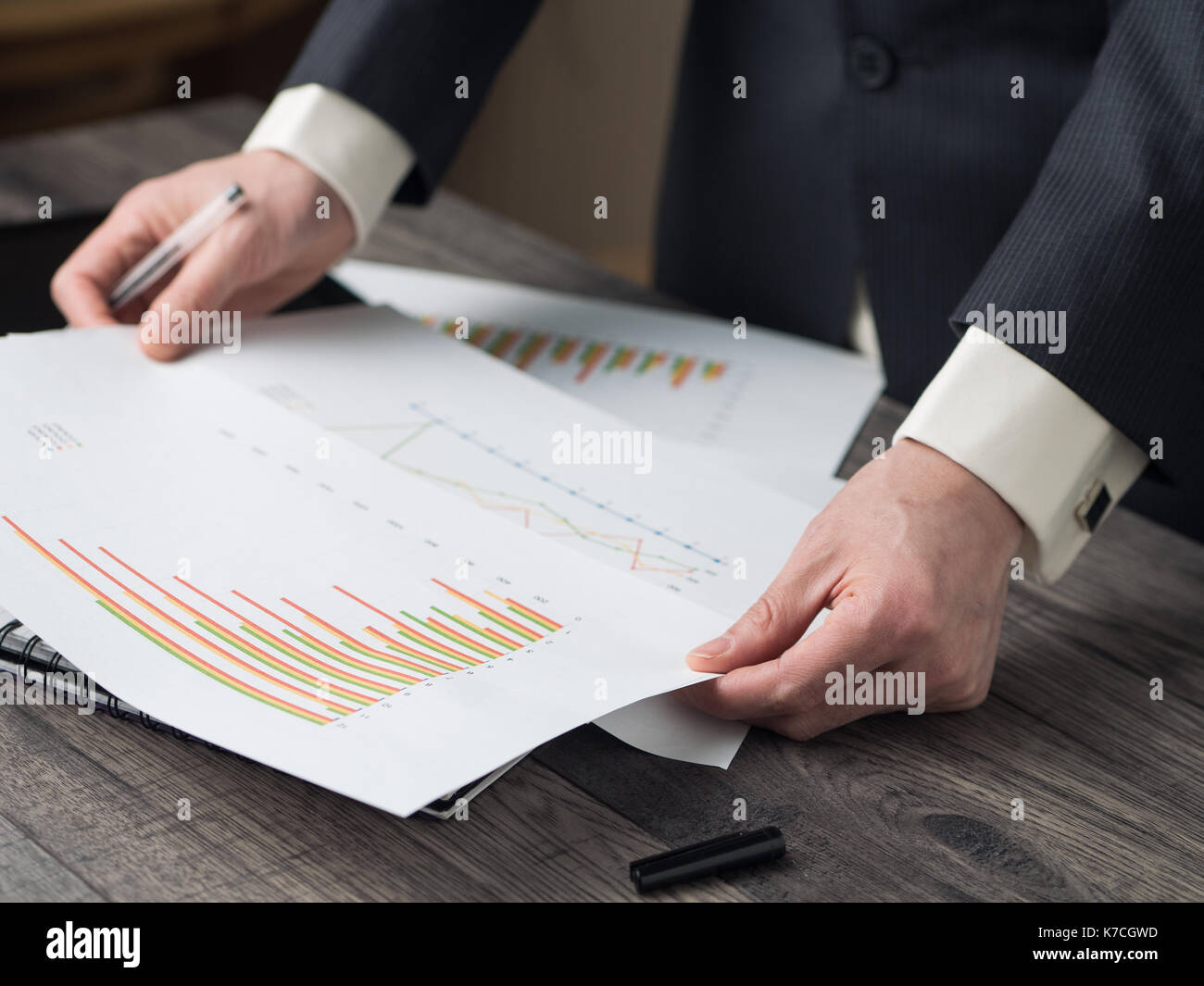 Business man hold a pen checking bar chart Stock Photo - Alamy
