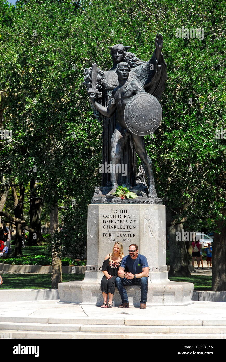 Couple sitting in front of the Confederate Defenders of Charleston statue in White Point Gardens on the Battery in Charleston, South Carolina Stock Photo
